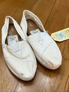 Woman’s Toms white w/blue stitching shoe. Size 9. NWT! Never worn! Cute + comfy!